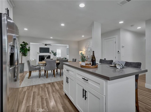 2867 Turnbull St, Oceanside, CA 92054 - kitchen featuring stainless steel refrigerator with ice dispenser, dark countertops, light wood-type flooring, white cabinets, and recessed lighting