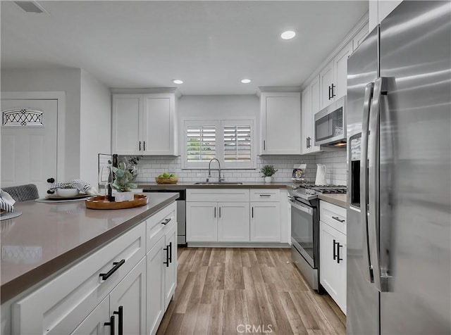 2867 Turnbull St, Oceanside, CA 92054 - kitchen with stainless steel appliances, decorative backsplash, light wood-style flooring, white cabinetry, and recessed lighting