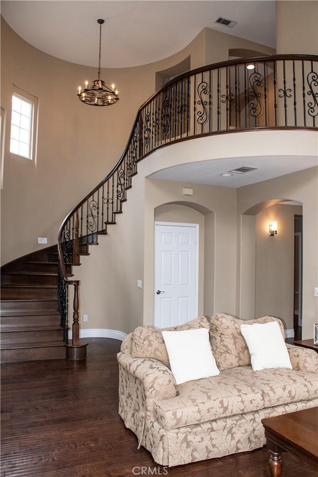 1671 Fairway Dr, Corona, CA 92883 - living room with arched walkways, a towering ceiling, dark wood-style flooring, a chandelier, and stairway