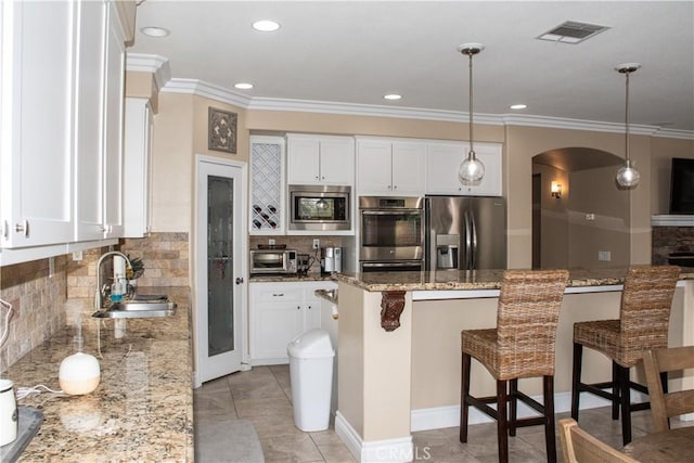 1671 Fairway Dr, Corona, CA 92883 - kitchen with stainless steel appliances, arched walkways, backsplash, ornamental molding, and a kitchen bar