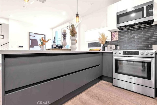 1131/2 N Manhattan Pl, Los Angeles, CA 90004 - kitchen featuring appliances with stainless steel finishes, gray cabinetry, modern cabinets, backsplash, and white cabinets