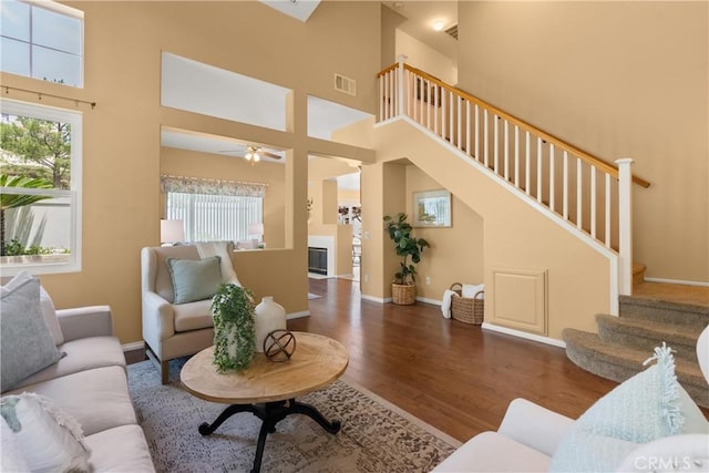 8 Chatri Cir, Lake Forest, CA 92610 - living area with stairs, wood finished floors, a ceiling fan, a towering ceiling, and a glass covered fireplace