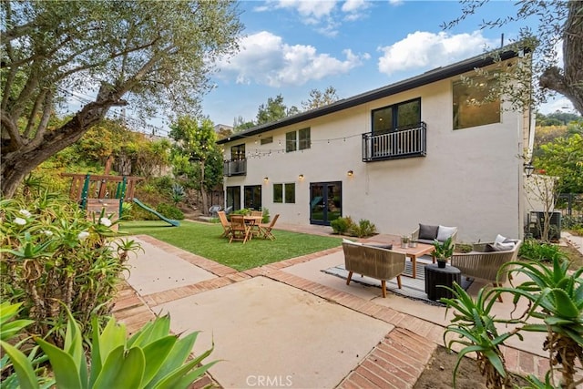 9767 Blantyre Dr, Beverly Hills, CA 90210 - back of house featuring a balcony, a patio area, a playground, an outdoor hangout area, and a lawn