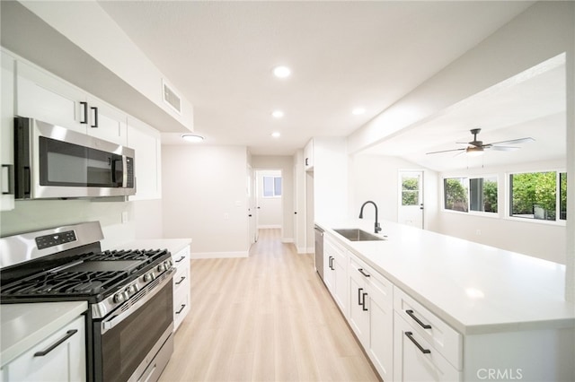 28610 Portsmouth Dr, Menifee, CA 92586 - kitchen featuring appliances with stainless steel finishes, light wood-style flooring, light countertops, white cabinetry, and recessed lighting