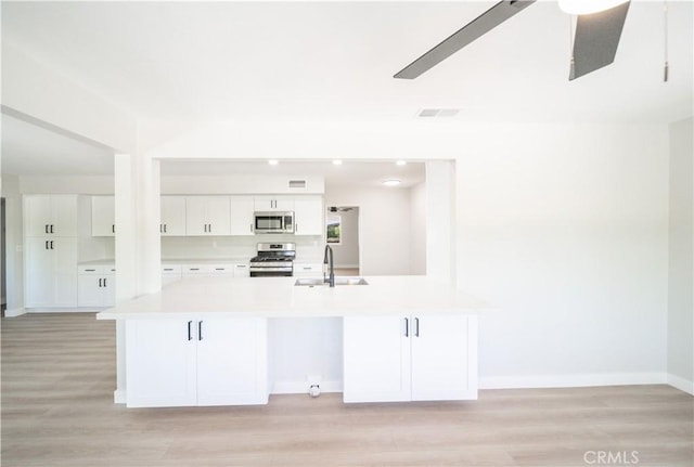 28610 Portsmouth Dr, Menifee, CA 92586 - kitchen featuring appliances with stainless steel finishes, white cabinets, light countertops, light wood finished floors, and recessed lighting