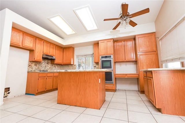 19385 Live Oak Ln, Lake Elsinore, CA 92530 - kitchen with under cabinet range hood, tasteful backsplash, a ceiling fan, a kitchen island, and light countertops