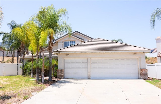 19385 Live Oak Ln, Lake Elsinore, CA 92530 - view of front of home with concrete driveway, stucco siding, an attached garage, and a gate
