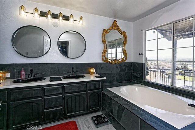 13665 Hidden Valley Rd, Victorville, CA 92395 - bathroom featuring double vanity, a garden tub, and wood finished floors