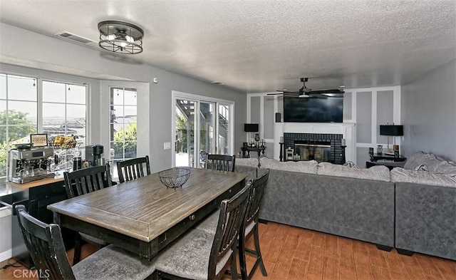 13665 Hidden Valley Rd, Victorville, CA 92395 - dining area with ceiling fan, a fireplace, wood finished floors, and a textured ceiling