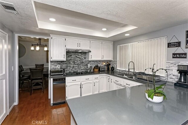 13665 Hidden Valley Rd, Victorville, CA 92395 - kitchen featuring a raised ceiling, dark wood-type flooring, white cabinets, backsplash, and under cabinet range hood