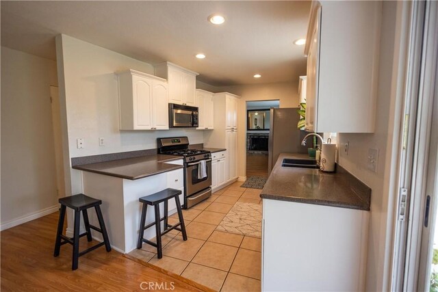 9025 La Vine St, Rancho Cucamonga, CA 91701 - kitchen featuring stainless steel appliances, dark countertops, white cabinets, recessed lighting, and a breakfast bar