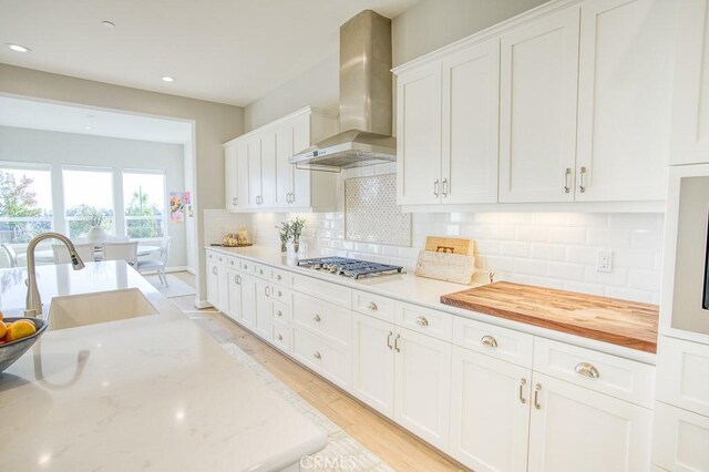 916 Trail View Pl, Nipomo, CA 93444 - kitchen featuring wall chimney range hood, stainless steel gas stovetop, white cabinetry, tasteful backsplash, and light wood finished floors