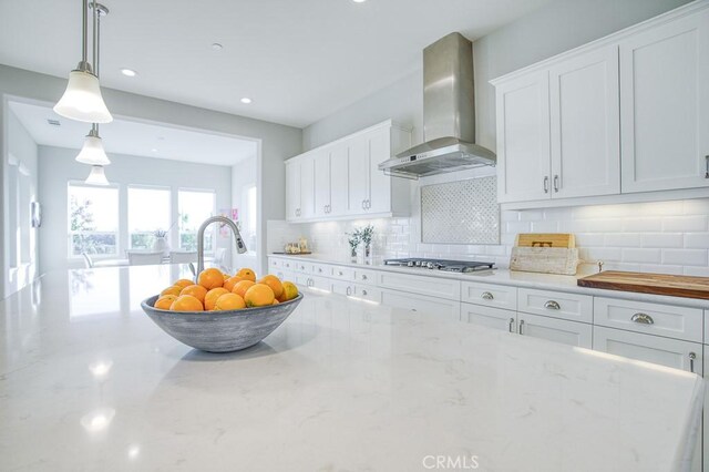 916 Trail View Pl, Nipomo, CA 93444 - kitchen with wall chimney range hood, stainless steel gas cooktop, decorative backsplash, white cabinetry, and hanging light fixtures