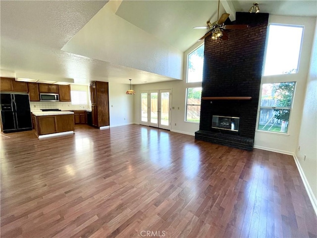 659 Royal Arch Ct, Merced, CA 95340 - unfurnished living room with a ceiling fan, dark wood-style flooring, a fireplace, high vaulted ceiling, and beam ceiling