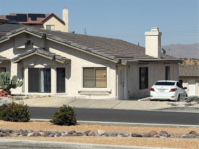 12411 Spring Vly, Victorville, CA 92395 - rear view of property with a chimney, stucco siding, a mountain view, and a tile roof