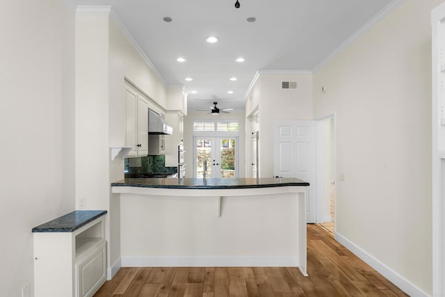 3647 Paseo Vista Famosa, Rancho Santa Fe, CA 92091 - kitchen with under cabinet range hood, crown molding, a peninsula, light wood-style floors, and white cabinetry