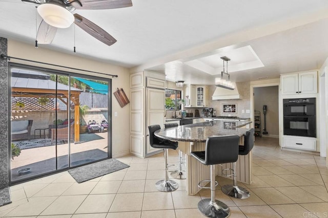 26267 Bellemore Dr, Ramona, CA 92065 - kitchen with premium range hood, a kitchen bar, dark stone countertops, a center island, and a raised ceiling