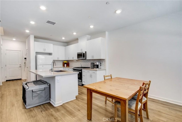 3934 Lavine Way Unit 108, Corona, CA 92883 - kitchen featuring appliances with stainless steel finishes, light countertops, tasteful backsplash, white cabinets, and an island with sink