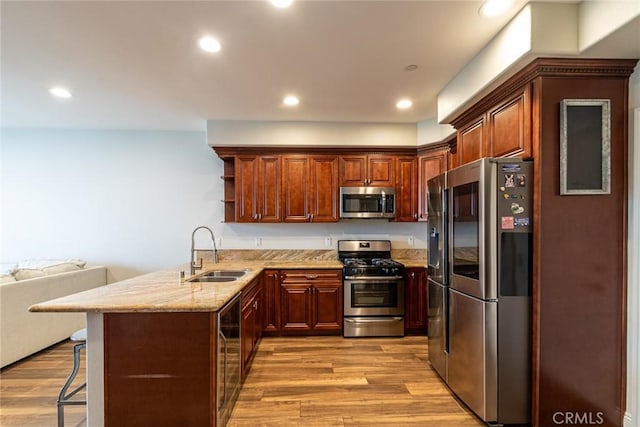 7019 Passons Blvd, Pico Rivera, CA 90660 - kitchen with stainless steel appliances, light wood finished floors, a peninsula, light stone countertops, and a kitchen bar