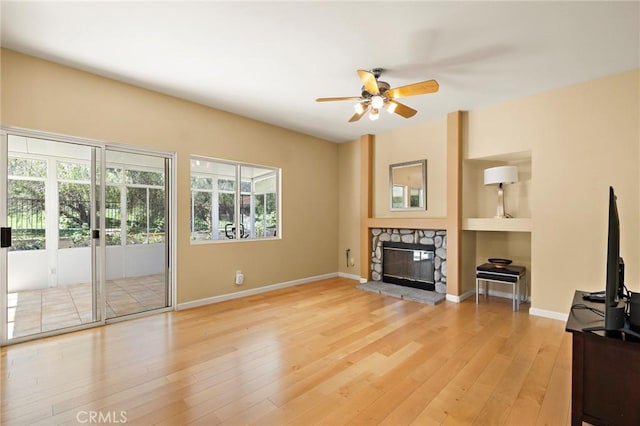 33087 Corte Ganso, Temecula, CA 92592 - unfurnished living room featuring ceiling fan, light wood-style flooring, a fireplace, and built in shelves