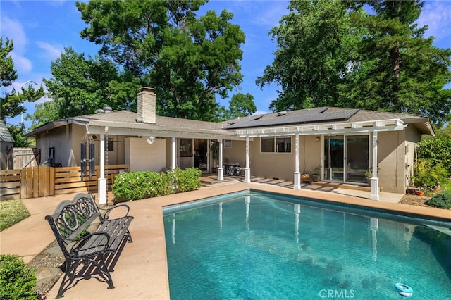 7 Calgary Ln, Chico, CA 95926 - rear view of house with a patio, roof mounted solar panels, a chimney, an outdoor pool, and stucco siding
