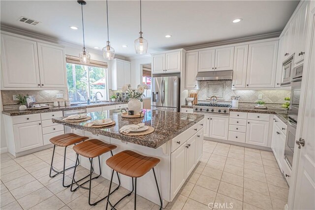 26511 Brooks Cir, Stevenson Ranch, CA 91381 - kitchen with stainless steel appliances, under cabinet range hood, light tile patterned floors, a kitchen island, and tasteful backsplash