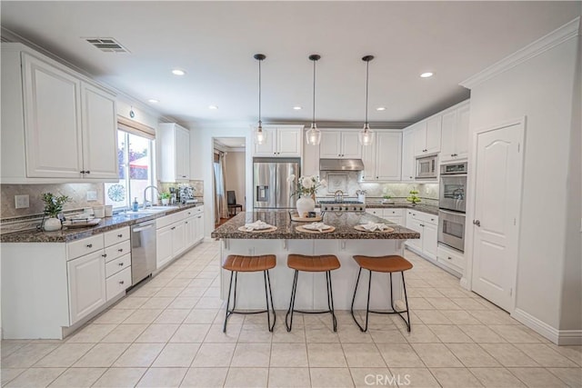26511 Brooks Cir, Stevenson Ranch, CA 91381 - kitchen with appliances with stainless steel finishes, light tile patterned floors, backsplash, a center island, and crown molding