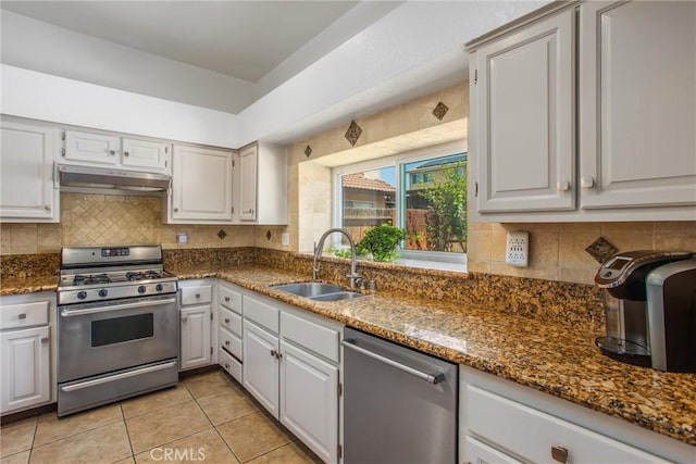 26490 Mapleridge Way, Moreno Valley, CA 92555 - kitchen with appliances with stainless steel finishes, under cabinet range hood, light tile patterned flooring, tasteful backsplash, and dark stone counters