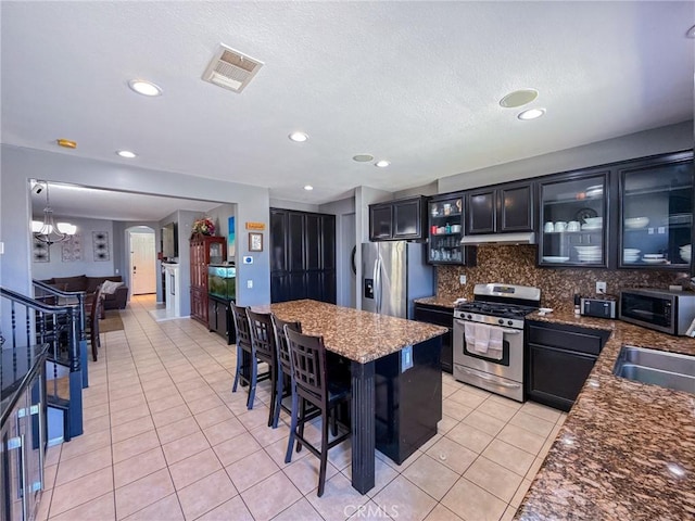 2753 Hornbeam Rd, Palmdale, CA 93551 - kitchen with stainless steel appliances, light tile patterned floors, tasteful backsplash, under cabinet range hood, and arched walkways