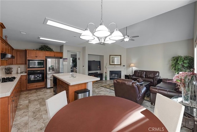 2175 Lester Ave, Clovis, CA 93619 - dining space featuring a ceiling fan, a fireplace, a chandelier, and vaulted ceiling