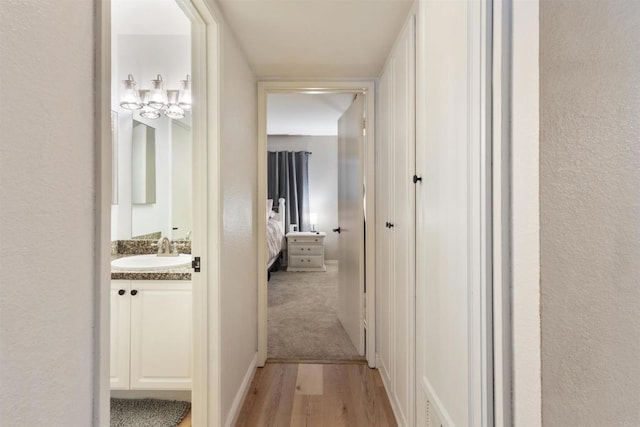 17119 W Bernardo Dr Unit 105, San Diego, CA 92127 - corridor featuring light wood finished floors, a textured wall, and a chandelier