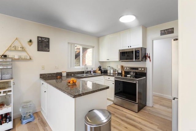 17119 W Bernardo Dr Unit 105, San Diego, CA 92127 - kitchen with appliances with stainless steel finishes, a peninsula, light wood-type flooring, white cabinets, and dark stone countertops