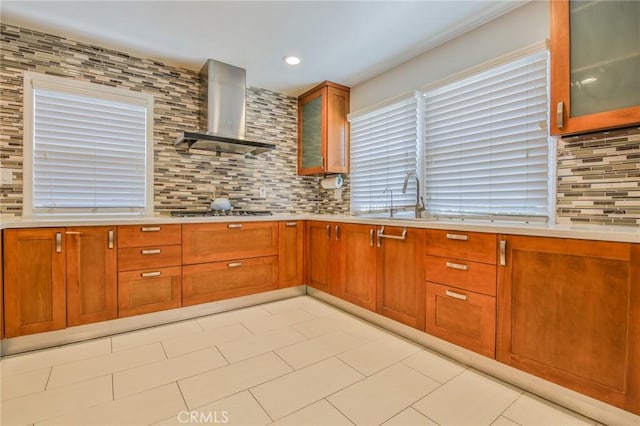 12818 Ramsey Dr, La Mirada, CA 90638 - kitchen featuring wall chimney exhaust hood, decorative backsplash, light countertops, stainless steel gas stovetop, and brown cabinets