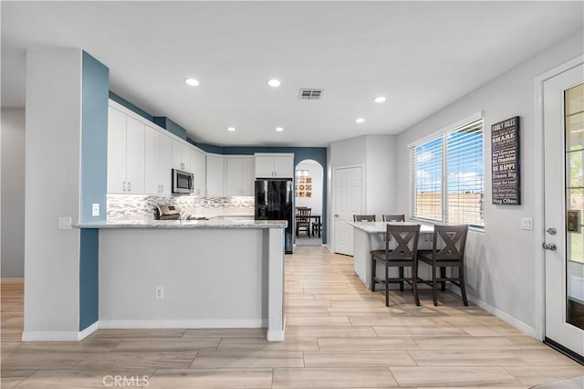 4604 Trojan Ct, Lancaster, CA 93536 - kitchen with stainless steel appliances, light wood-style floors, white cabinets, a peninsula, and recessed lighting