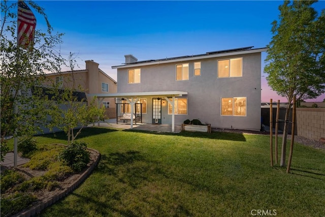 4604 Trojan Ct, Lancaster, CA 93536 - back of property at dusk featuring solar panels, a patio area, a fenced backyard, and stucco siding