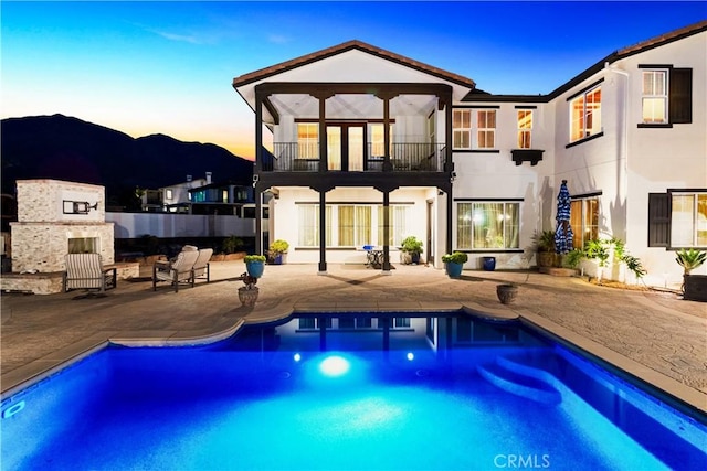 5156 Branding Iron Pl, Rancho Cucamonga, CA 91739 - back of property at dusk with a balcony, a patio, stucco siding, and an outdoor pool
