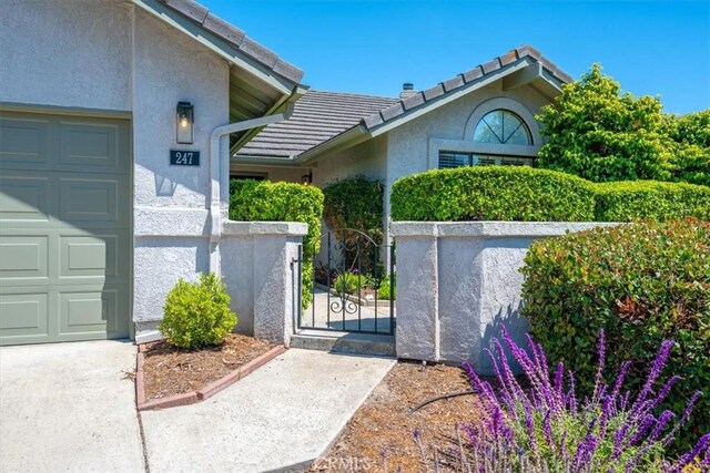 247 Oakwood Ct, Arroyo Grande, CA 93420 - property entrance with stucco siding, a garage, a gate, and a tiled roof