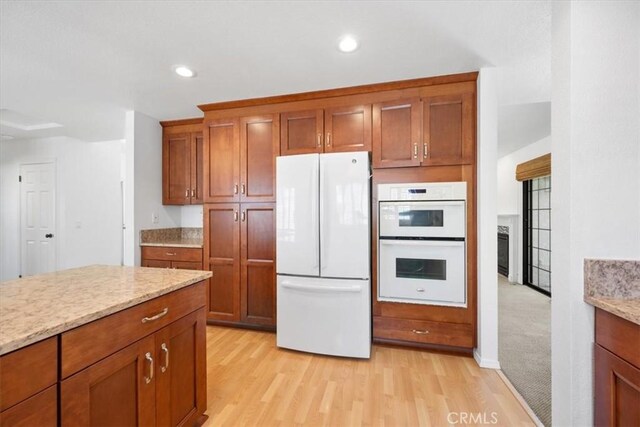 247 Oakwood Ct, Arroyo Grande, CA 93420 - kitchen with white appliances, brown cabinets, light wood finished floors, light stone counters, and recessed lighting