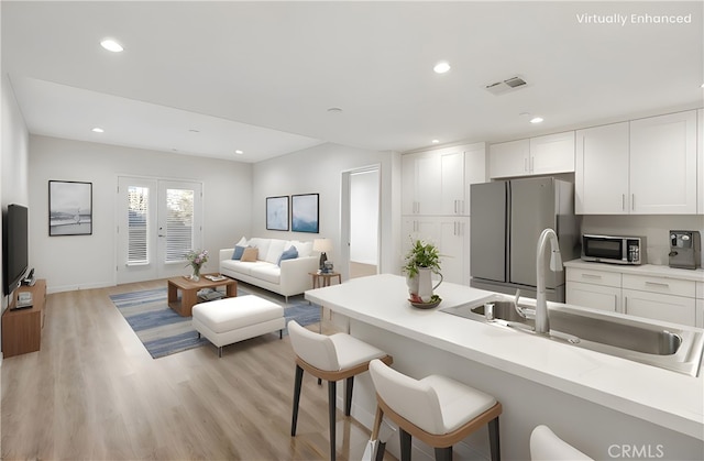 419 N Chandler Ave Unit 520, Monterey Park, CA 91754 - kitchen with freestanding refrigerator, stainless steel microwave, a kitchen bar, light wood-style flooring, and white cabinets