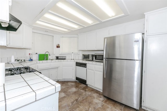 44105 Acacia St, Lancaster, CA 93535 - kitchen with appliances with stainless steel finishes, tile countertops, exhaust hood, white cabinetry, and stone finish floors