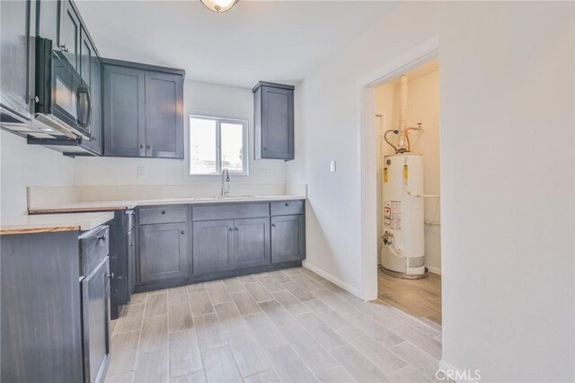 223 E 83rd St, Los Angeles, CA 90003 - kitchen with water heater, wood finish floors, black microwave, and light countertops