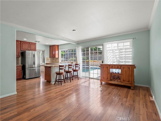 22905 Las Mananitas Dr, Valencia, CA 91354 - kitchen with freestanding refrigerator, crown molding, a kitchen bar, hardwood / wood-style floors, and light countertops