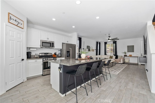 4360 Rima Dr, Fontana, CA 92336 - kitchen featuring appliances with stainless steel finishes, a kitchen breakfast bar, a center island, light wood-style floors, and white cabinetry