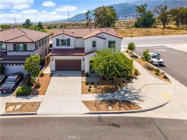 4360 Rima Dr, Fontana, CA 92336 - mediterranean / spanish-style house featuring a mountain view, stucco siding, a tile roof, a garage, and concrete driveway
