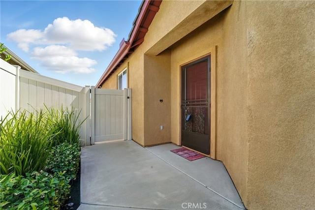 1544 Big Bnd, Beaumont, CA 92223 - view of exterior entry with stucco siding, a gate, and a patio