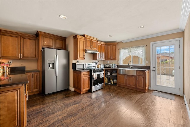 2730 Hayes Ave, Long Beach, CA 90810 - kitchen featuring appliances with stainless steel finishes, brown cabinetry, under cabinet range hood, dark wood-type flooring, and recessed lighting
