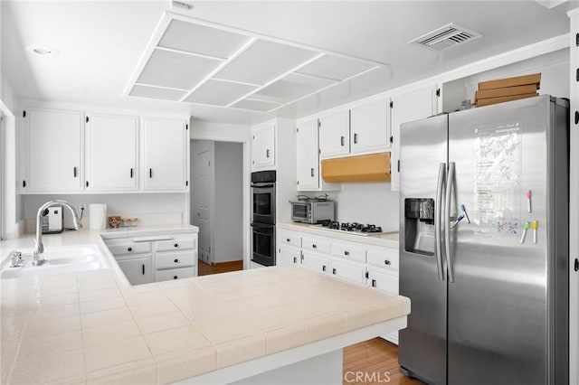 4035 Ellenita Ave, Tarzana, CA 91356 - kitchen featuring stainless steel fridge with ice dispenser, double wall oven, a peninsula, white cabinets, and tile counters