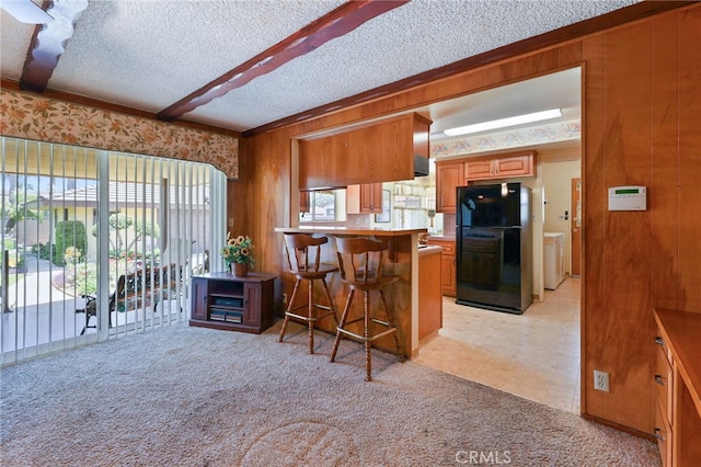 12429 Baker Ave, Chino, CA 91710 - kitchen with freestanding refrigerator, brown cabinetry, a breakfast bar, a peninsula, and a textured ceiling