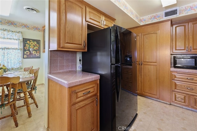 12429 Baker Ave, Chino, CA 91710 - kitchen featuring black appliances, backsplash, tile countertops, and brown cabinetry