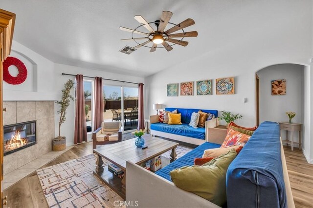 3715 Surrey, Yucca Valley, CA 92284 - living area with a ceiling fan, wood finished floors, arched walkways, vaulted ceiling, and a tile fireplace